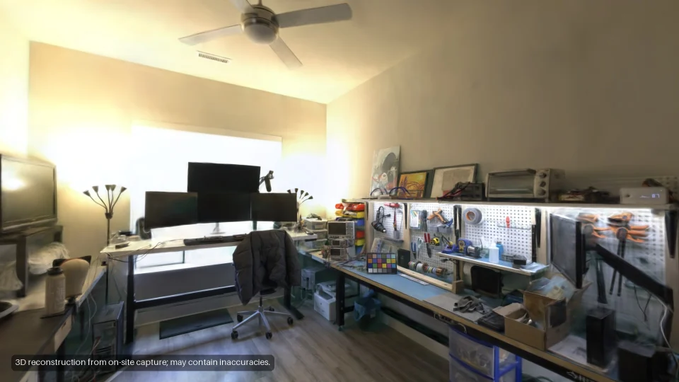 The living area: a desk with three monitors and a pegboard wall.